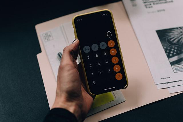 iPhone calculator being held above documents and files